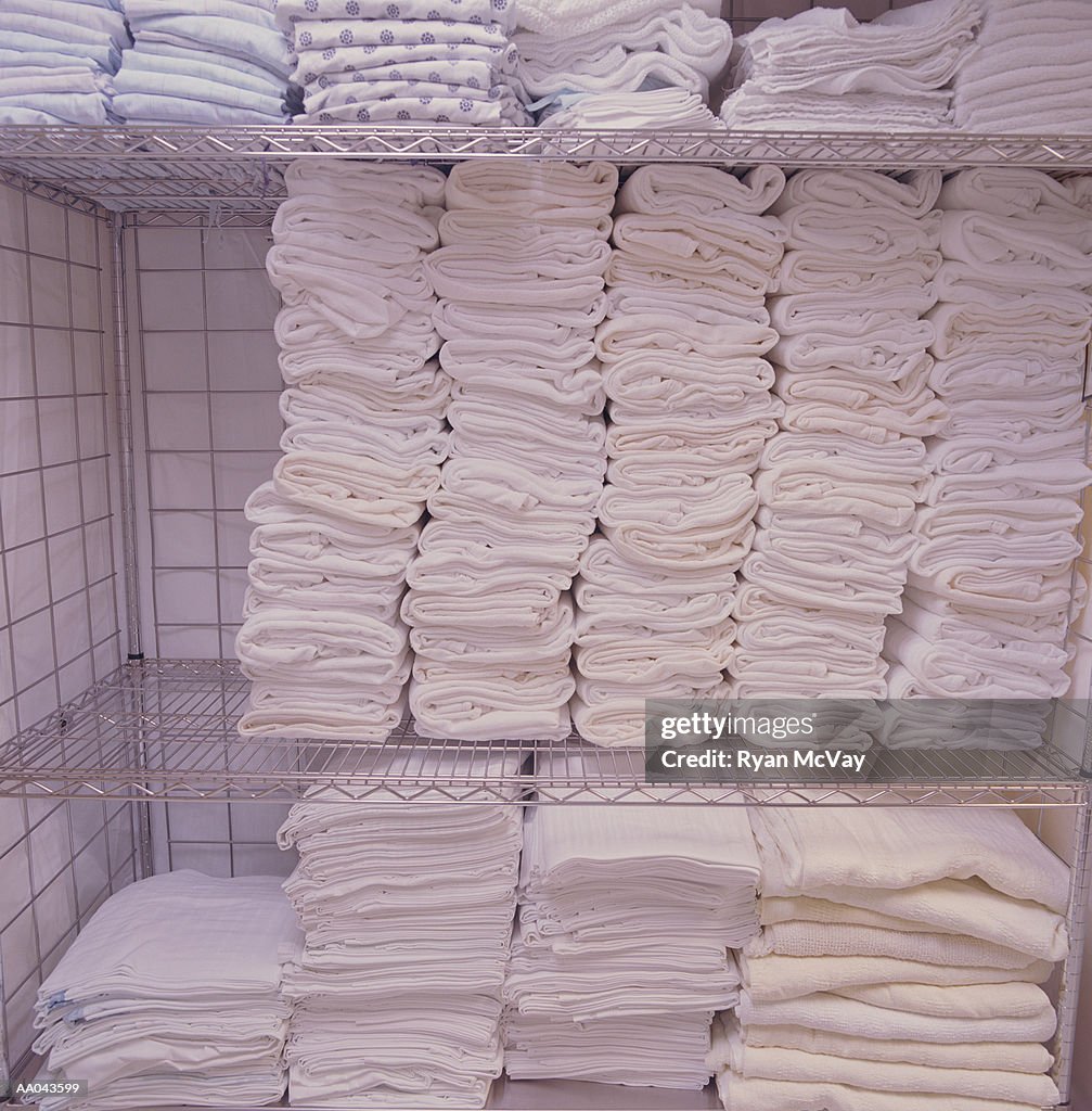 Sheets, towels and gowns stacked on metal rack in hospital