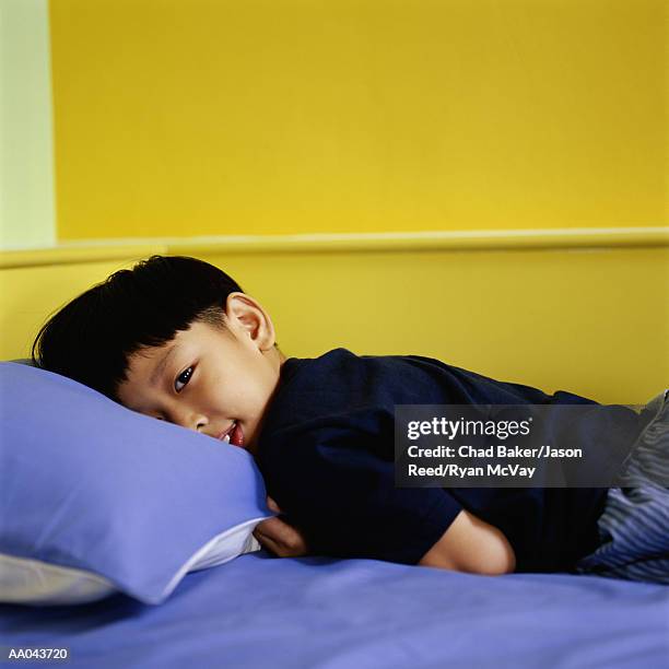 boy (7-9) lying on bed - reed bed stock pictures, royalty-free photos & images