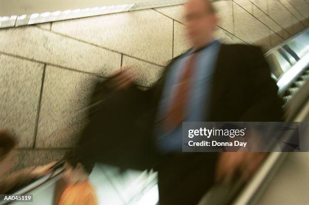 businessman riding down escalator (blurred motion) - donna matura - fotografias e filmes do acervo