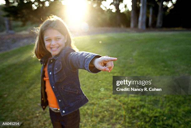 girl (7-9) outdoors, pointing finger - nancy green stockfoto's en -beelden