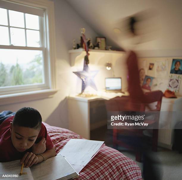 boy working on homework, brother walking by - bedtime stories stock-fotos und bilder