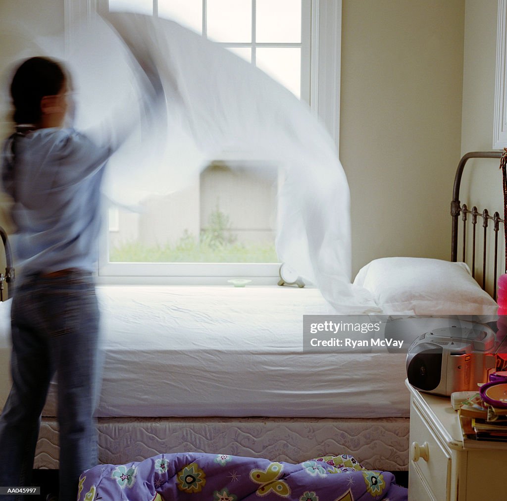 Girl (10-12) making bed, rear view (blurred motion)