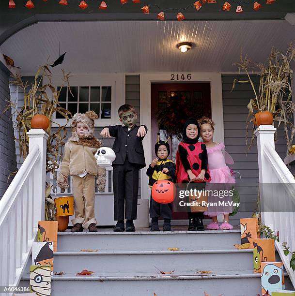 five children standing on porch, wearing halloween costumes, portrait - bear suit 個照片及圖片檔