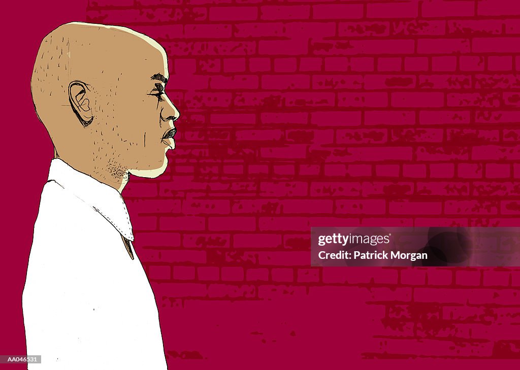 Man standing in front of brick wall, profile