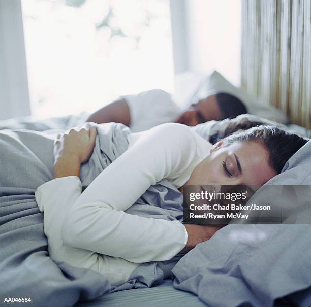 young man and woman sleeping in bed (focus on woman) - reed bed stock pictures, royalty-free photos & images