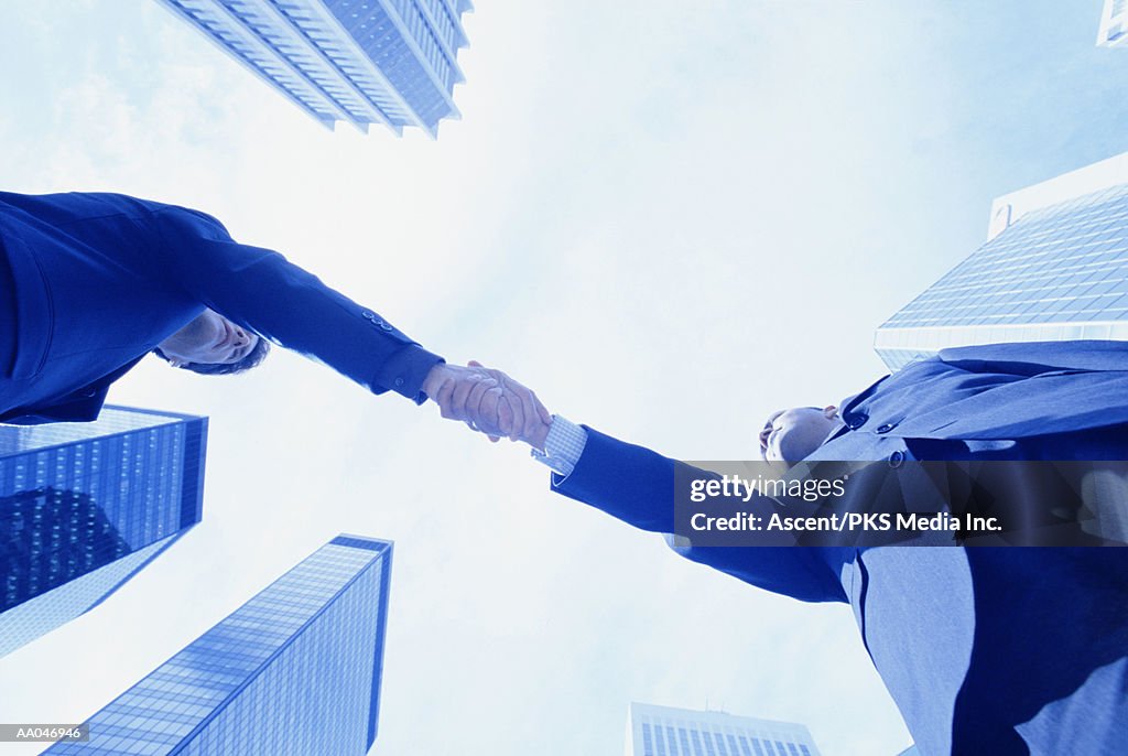 Businessmen shaking hands, view from below