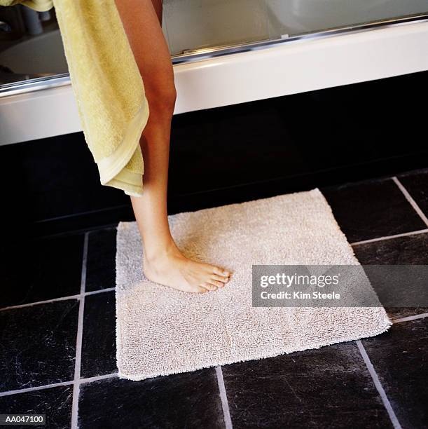 woman drying off after bath, low section, side view - bath mat stockfoto's en -beelden