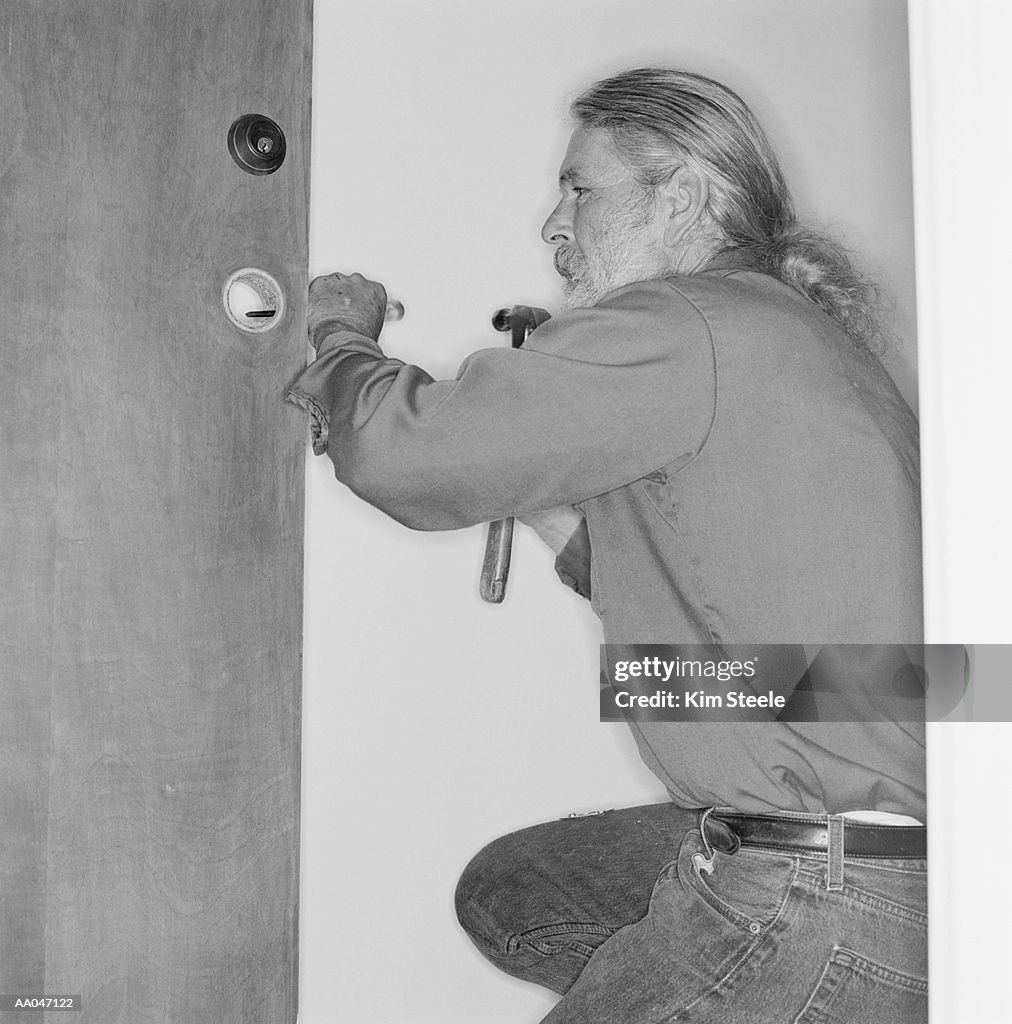 Locksmith installing lock, side view (B&W)