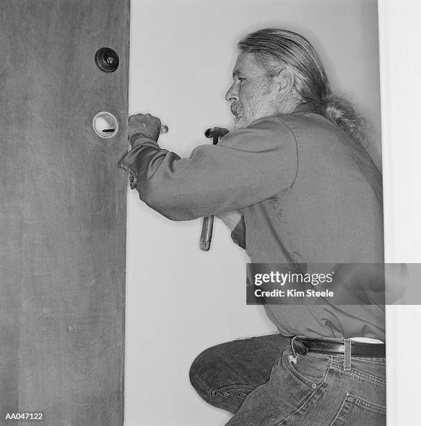 locksmith installing lock, side view (b&w) - installation of memorial honors victims of ghost ship fire in oakland stockfoto's en -beelden