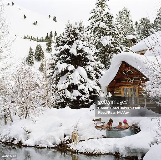 Three young adults in outdoor hot tub surrounded by snow