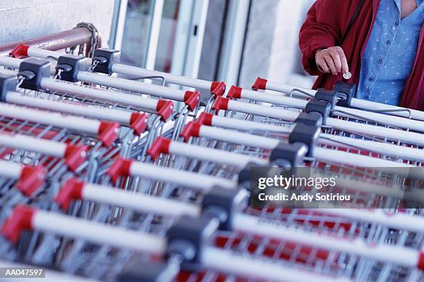 woman releasing for shopping cart with euro coin, mid section - releasing money stock pictures, royalty-free photos & images