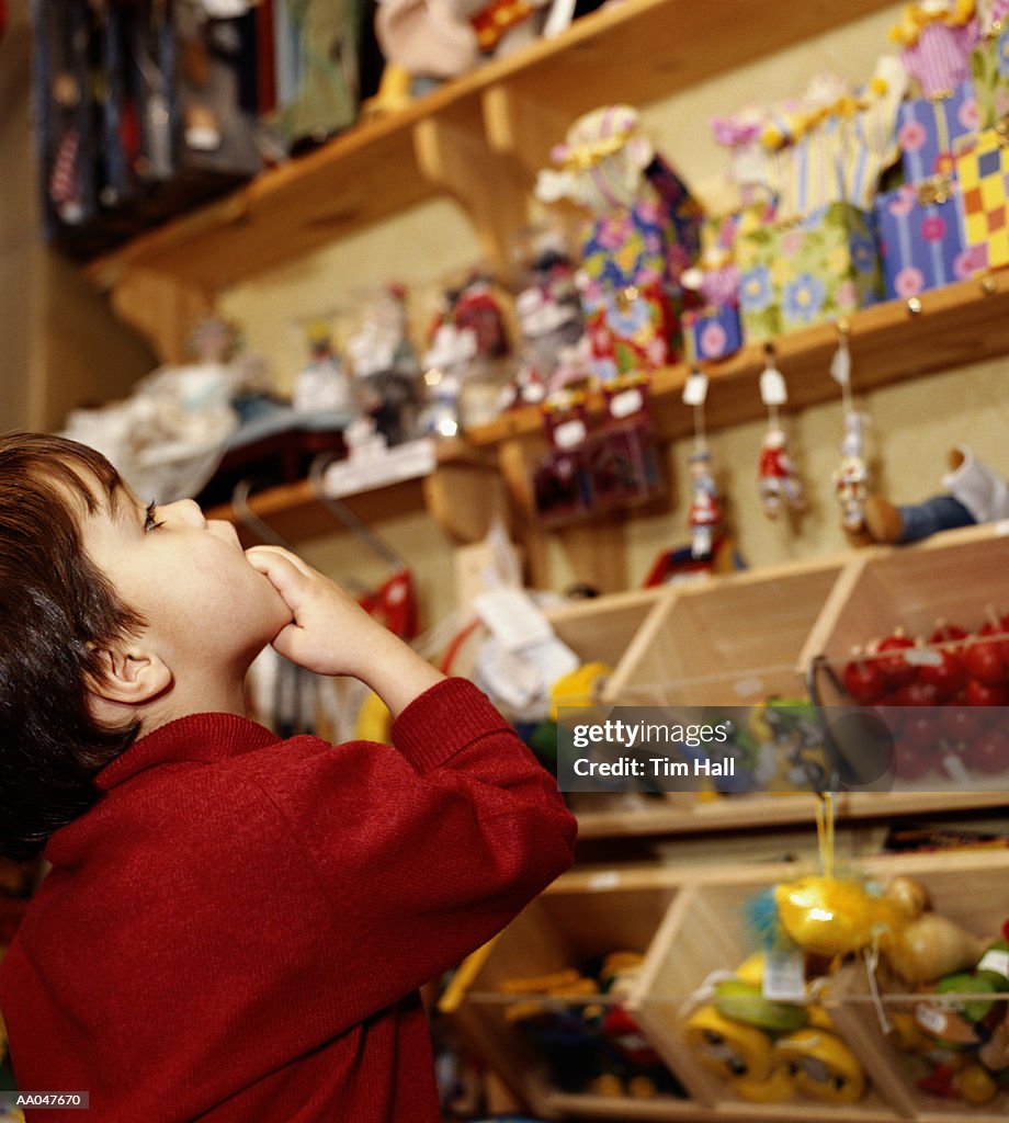 Boy (3-5) looking at toys in shop, side view