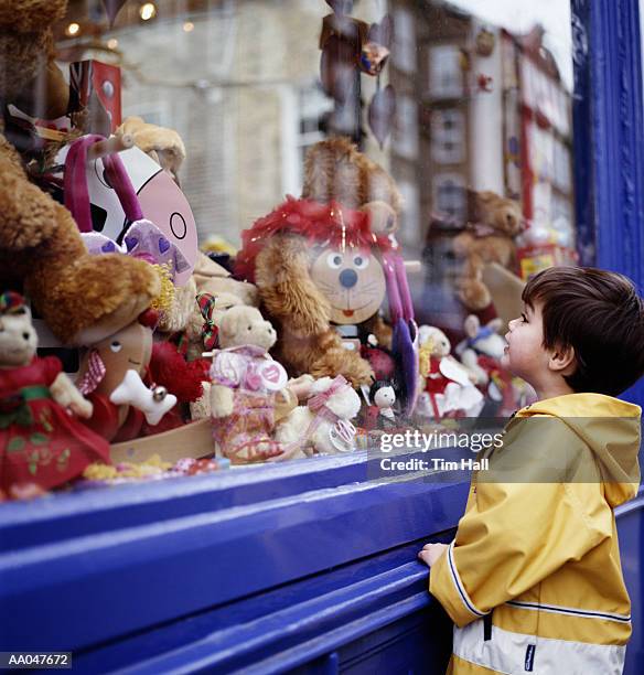 boy (3-5) looking at toys in shop window, side view - loja de brinquedos imagens e fotografias de stock