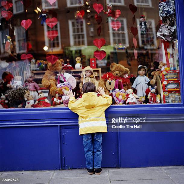 boy (3-5) looking at toys in toy shop window, rear view - loja de brinquedos imagens e fotografias de stock
