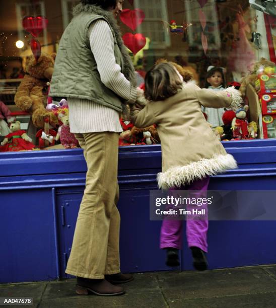 mother with daughter (4-6) looking in store window, rear view - desiderio foto e immagini stock