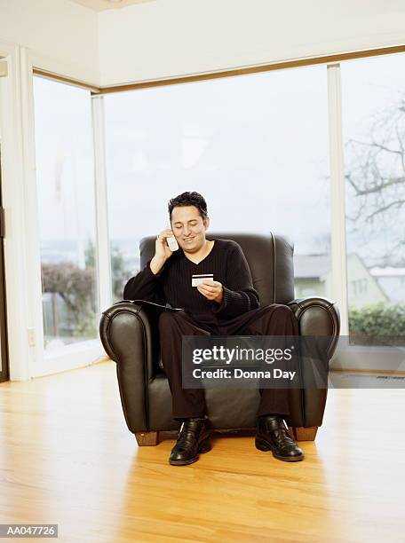 young man making credit card purchase over cordless phone - donna elegante stock-fotos und bilder
