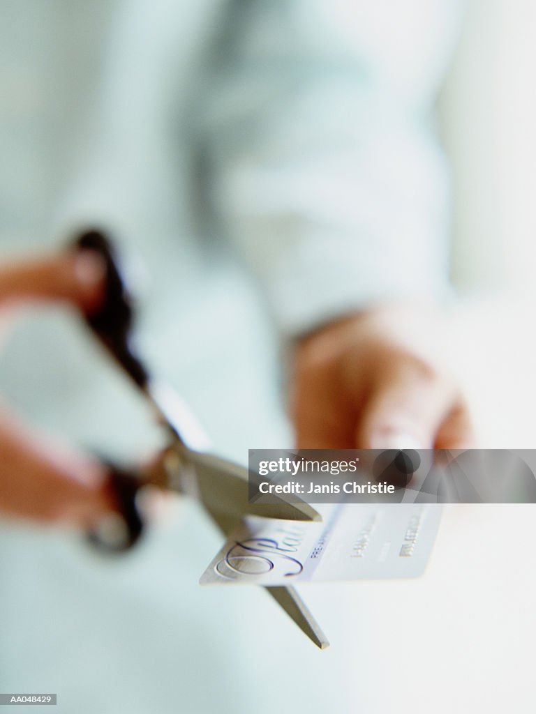 Woman cutting up credit card with scissors