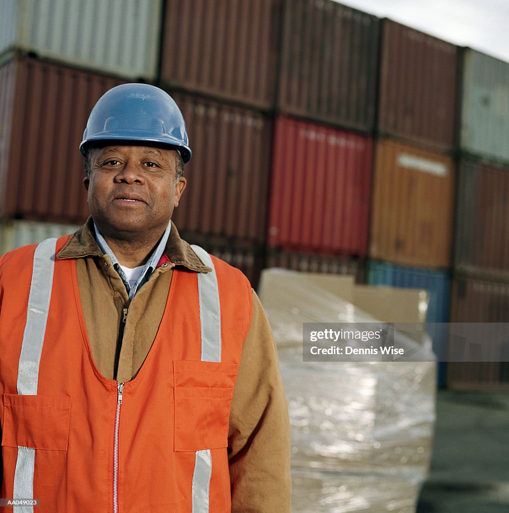 Man wearing hard hat in front of cargo containers, portrait