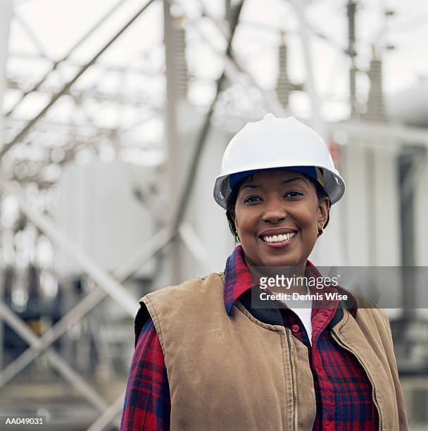 woman wearing hard hat in front of power station, portrait - black helmet stock pictures, royalty-free photos & images