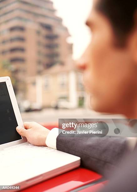 young businessman resting laptop on car roof soft focus, sideview - región metropolitana de santiago stockfoto's en -beelden