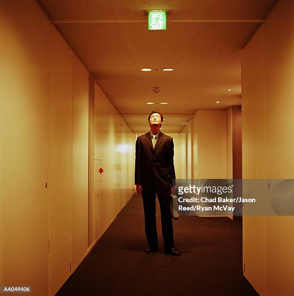 young businessman standing in corridor, looking up at sign - japanese exit sign stock pictures, royalty-free photos & images