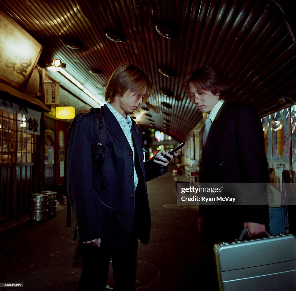 Young businessmen, carrying briefcases and dialing cell phones