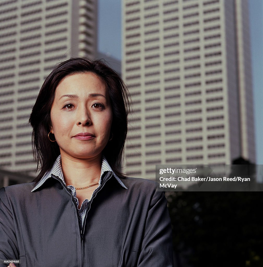 Businesswoman standing in front of skyscrapers, close-up, portrait