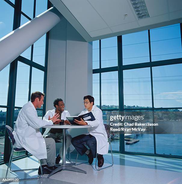 three research scientists in lab coats meeting at round table - round three bildbanksfoton och bilder