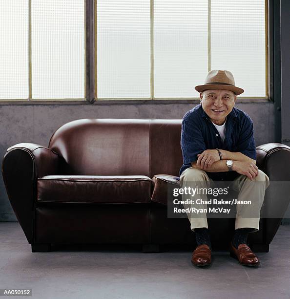 mature man sitting on small sofa, portrait - loveseat fotografías e imágenes de stock