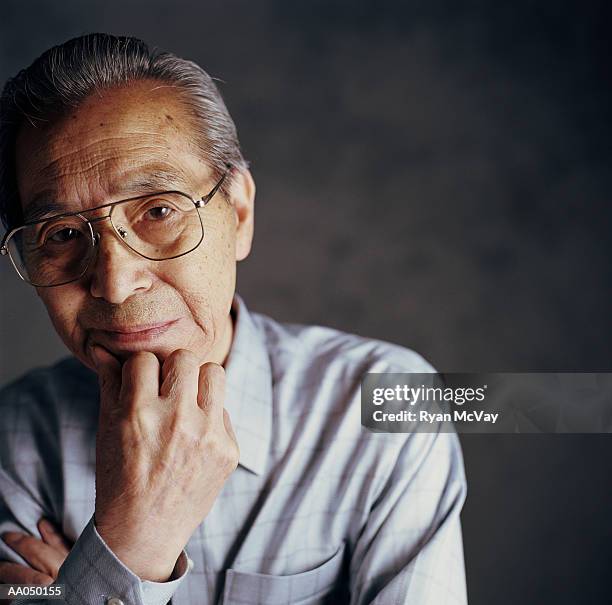 senior man resting chin on hand, close-up, portrait - japanese ol stockfoto's en -beelden