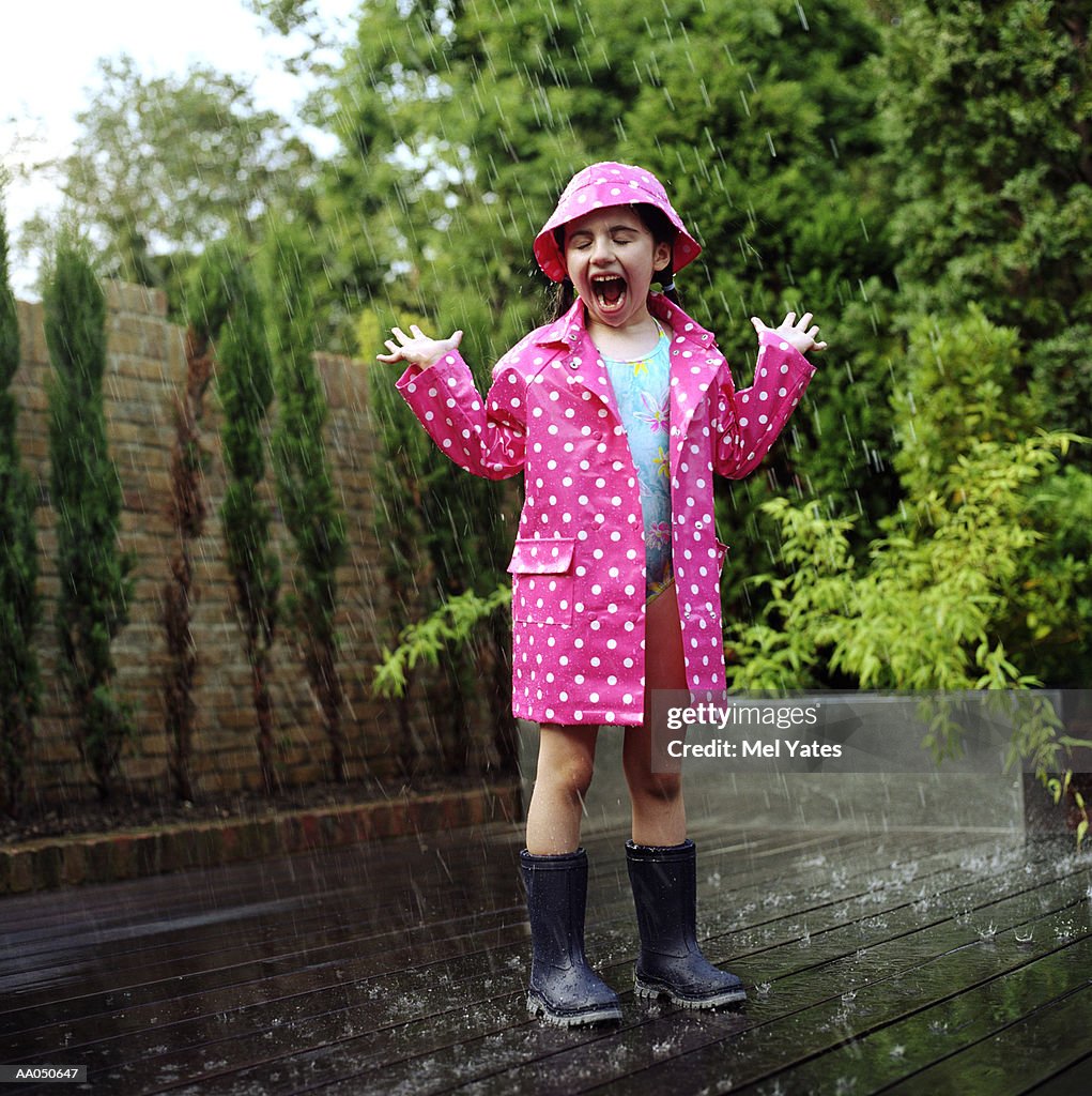 Girl (4-6) wearing  swimsuit and raincoat in rain