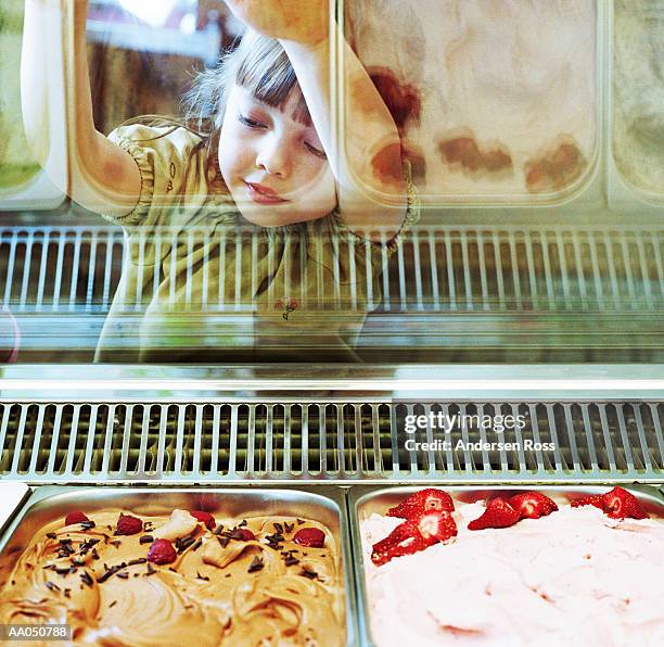 girl (5-7) looking at ice cream through glass case - ice cream parlour stock pictures, royalty-free photos & images