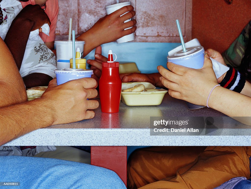 Friends eating food in booth at diner, side view, close up