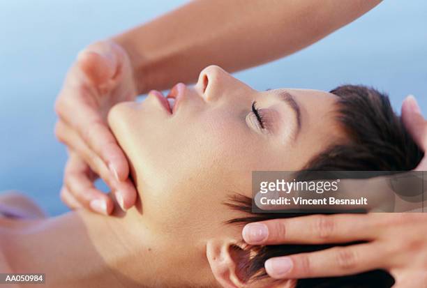 masseuse giving young woman face massage, close up, side view - facial massage stock pictures, royalty-free photos & images