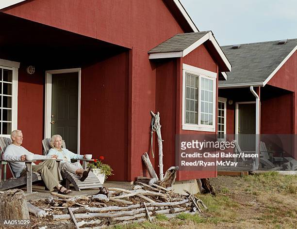 mature couple sitting on porch of beach cabin - baker beach stock pictures, royalty-free photos & images