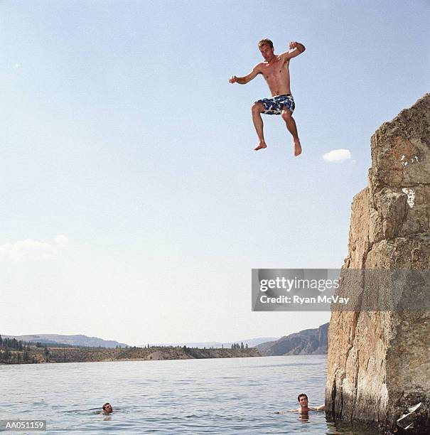 man jumping off cliff into lake - salto desde acantilado fotografías e imágenes de stock