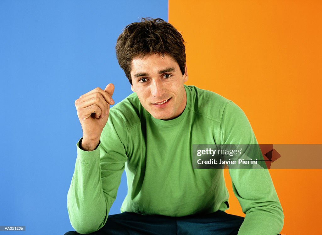 Young man sitting infront of colorful bakground, portrait