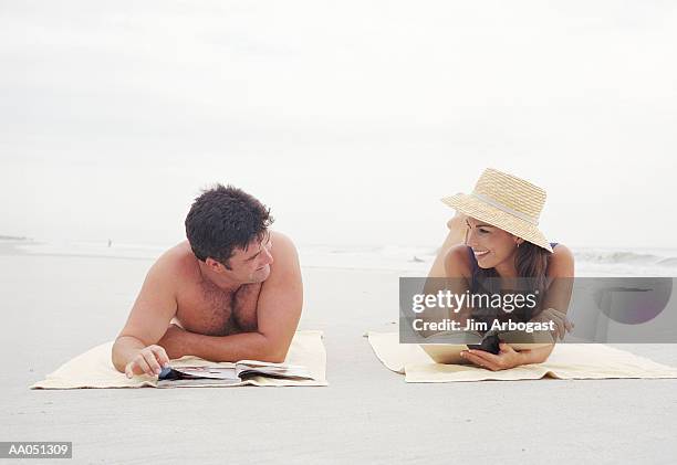 man and woman lying on beach reading book and magazine - magazine retreat day 2 stock pictures, royalty-free photos & images