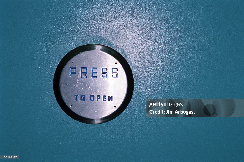 Metal 'press to open' button on a blue wall
