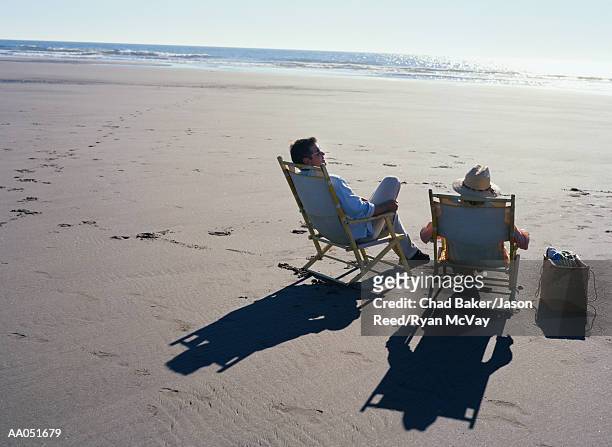 man and woman sitting on deck chairs on beach, rear view - baker beach stock pictures, royalty-free photos & images