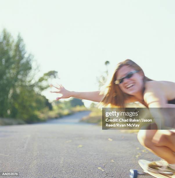 young woman crouching down on longboard (soft focus) - surfista de asfalto imagens e fotografias de stock