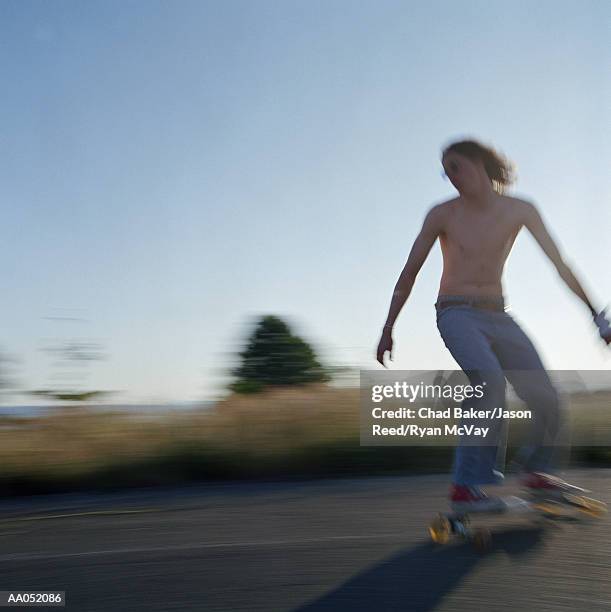 young man skating on longboard bare chested (blurred motion) - surfista de asfalto imagens e fotografias de stock