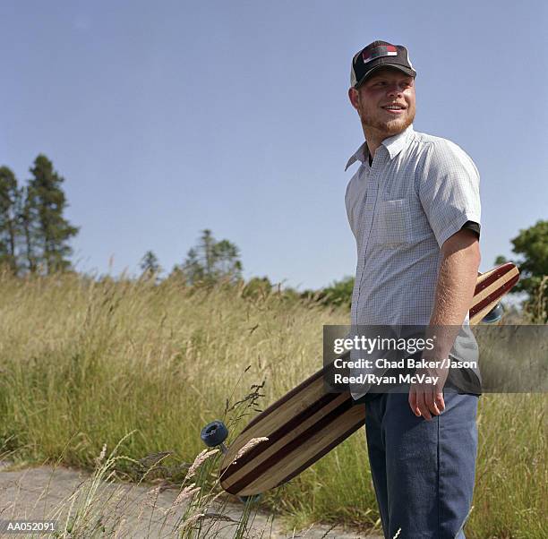 young man carrying longboard, portrait - surfista de asfalto imagens e fotografias de stock