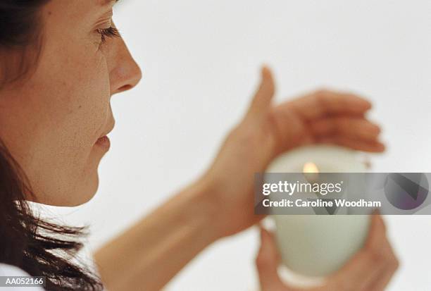 woman holding candle, shielding flame with hand (selective focus) - votive candle stock pictures, royalty-free photos & images