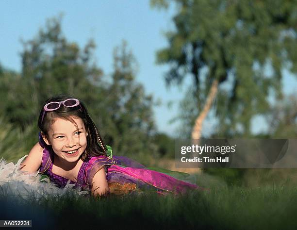 girl (6-8) wearing costume and feather boa, lying on grass - feather boa 個照片及圖片檔