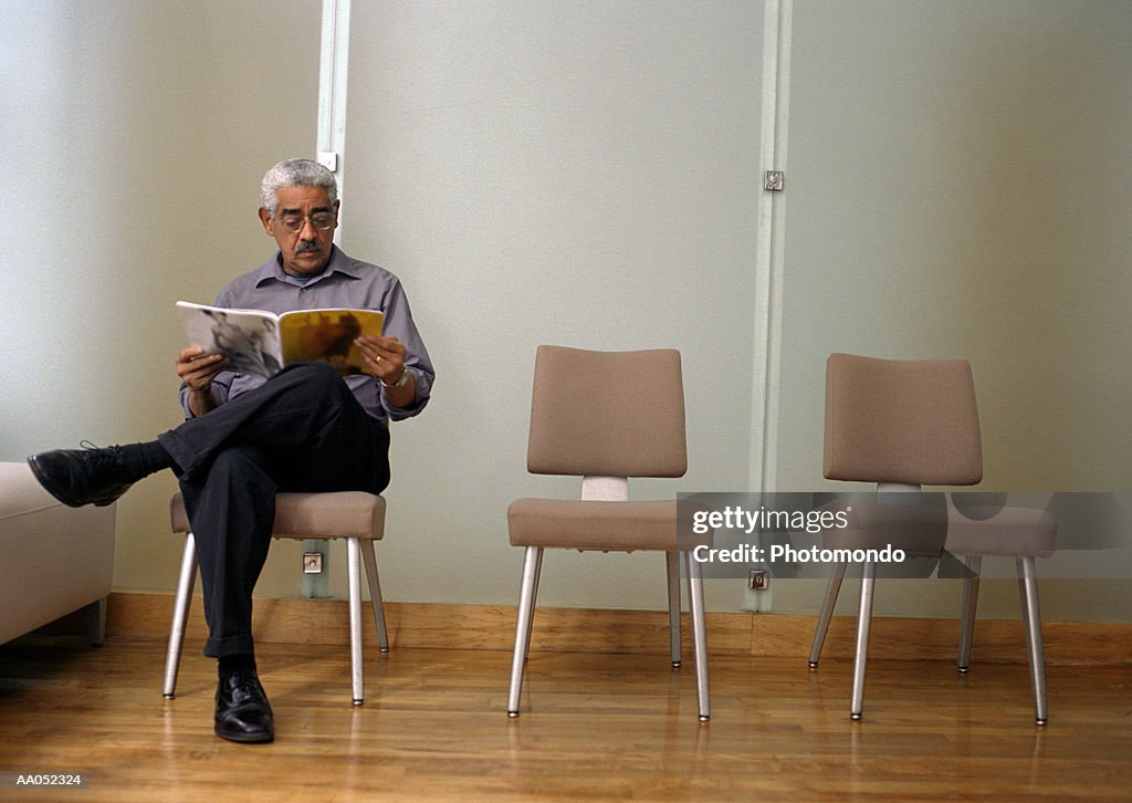 Mature man reading magazine in waiting room