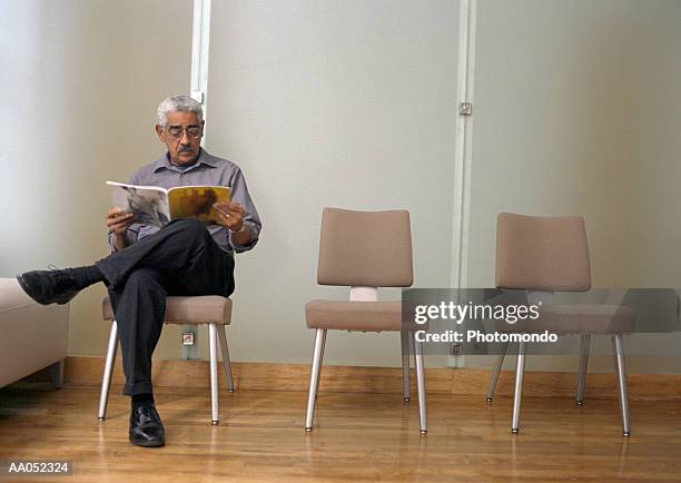 mature man reading magazine in waiting room - doctor sitting stock pictures, royalty-free photos & images