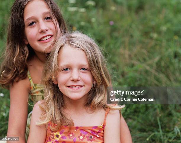 two sisters (7-9) sitting in grass field, high section, close-up - connie stock pictures, royalty-free photos & images