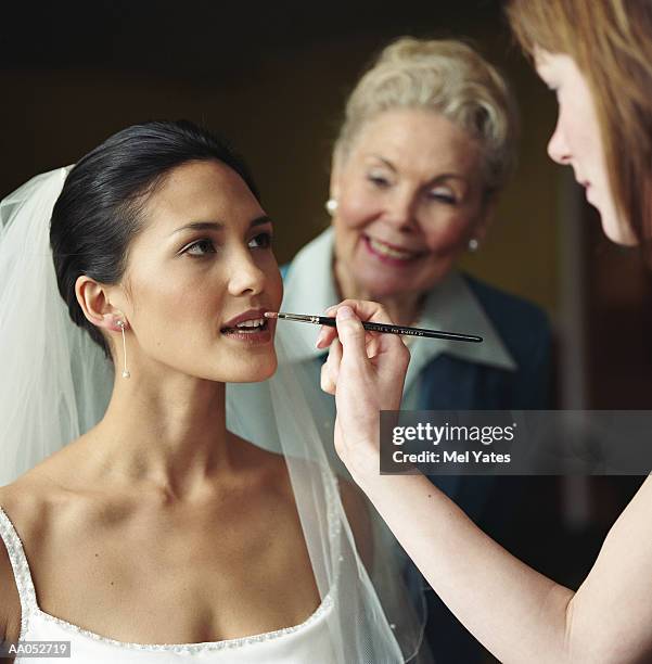 bride having lipstick applied while elderly woman looks over shoulder - maquillage professionnel photos et images de collection
