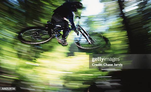 man jumping mountain bike on trail, low angle view (blurred motion) - footage technique stock pictures, royalty-free photos & images